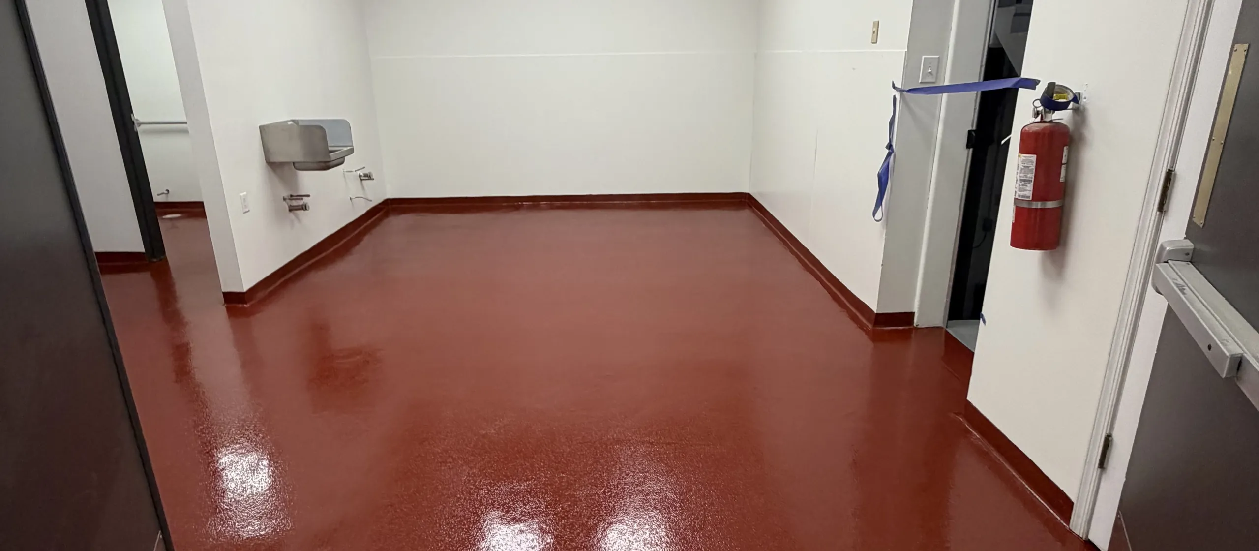 Tile red epoxy floor with a coved base in a commercial utility room
