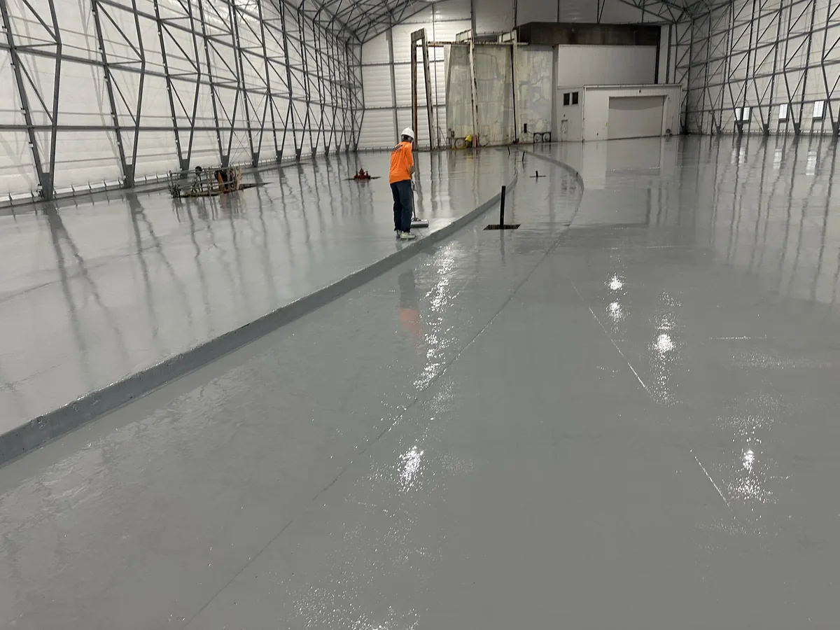 Crew spreading grey solid color epoxy across the floor of a decontamination enclosure at a nuclear power station