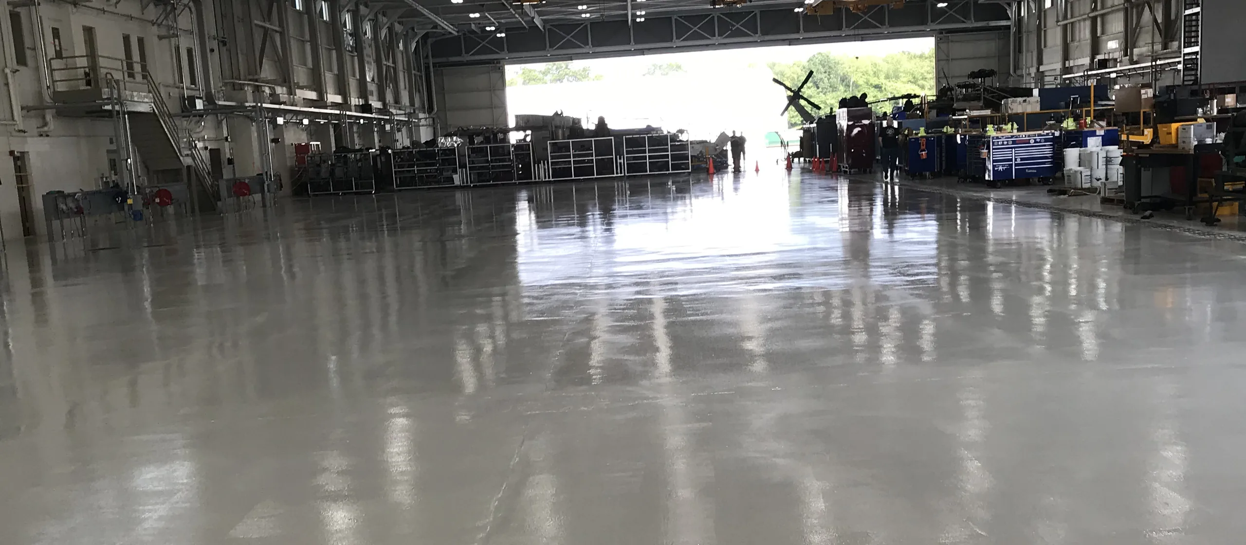 Solid color epoxy floor running the length of an aviation hangar with the main door open