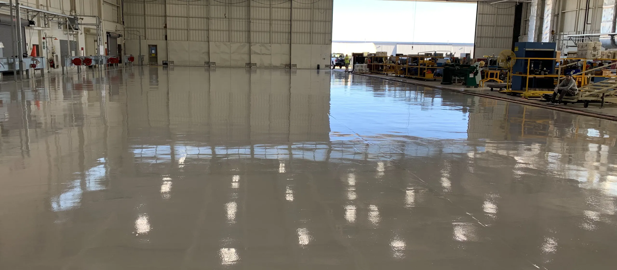 Gray solid color floor across an aircraft hangar with the door open