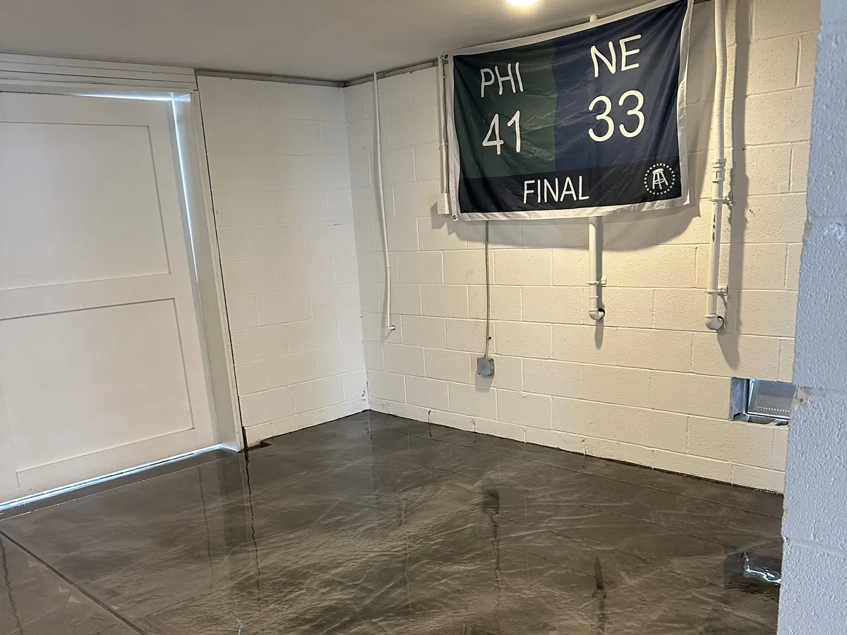 Dark metallic epoxy floor in a garage under an Eagles score banner