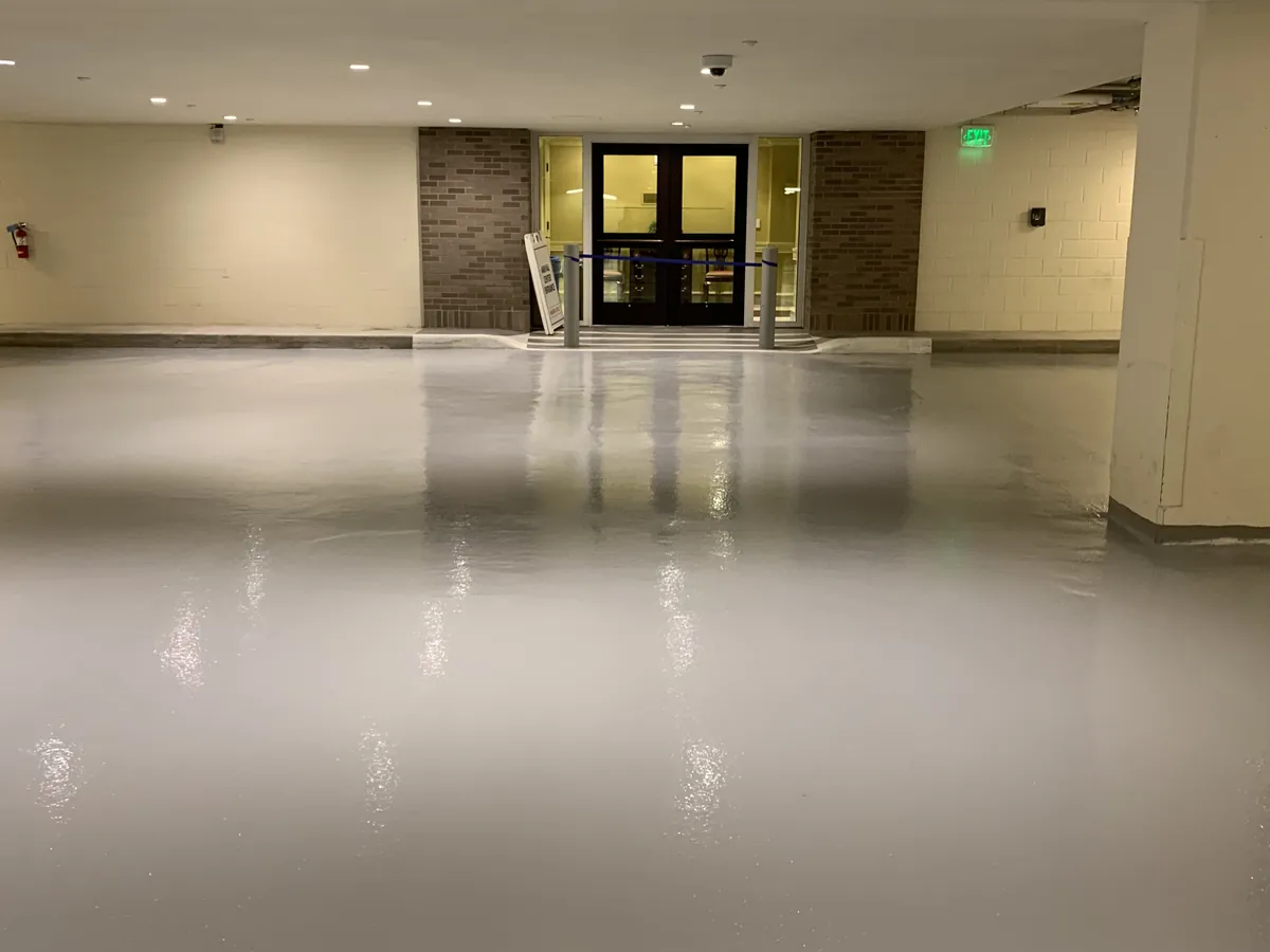 Grey epoxy floor running flat at a parking garage entrance
