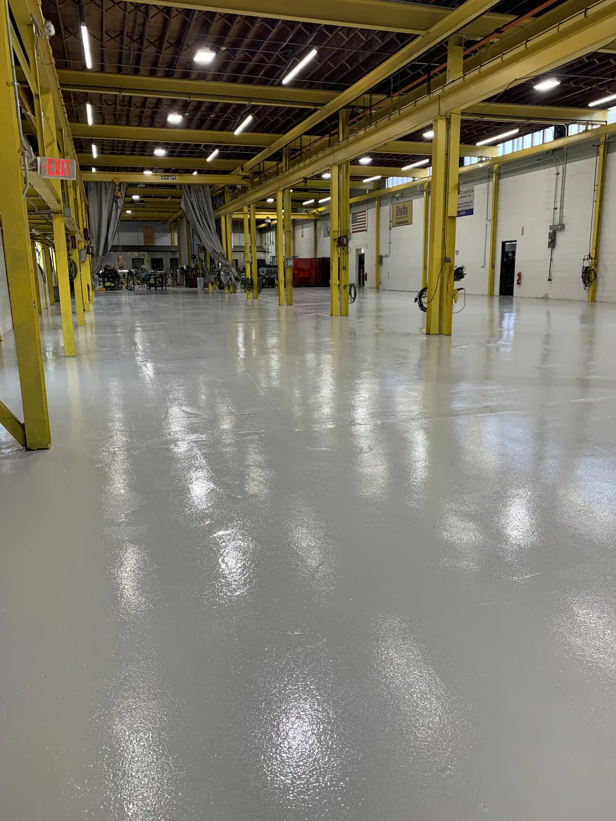 Coated floor down an auto service shop between yellow columns