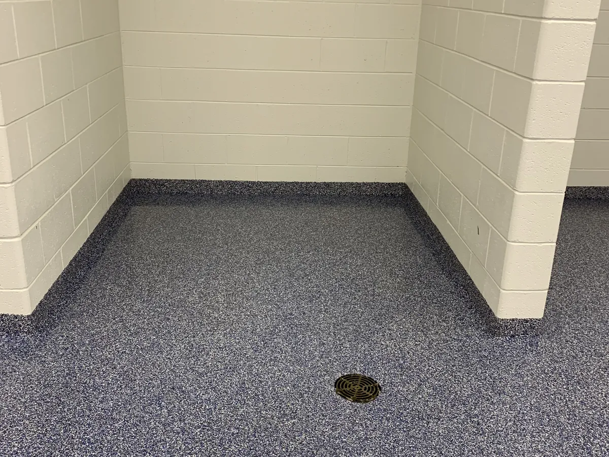 Blue quartz broadcast floor with a coved base and a floor drain