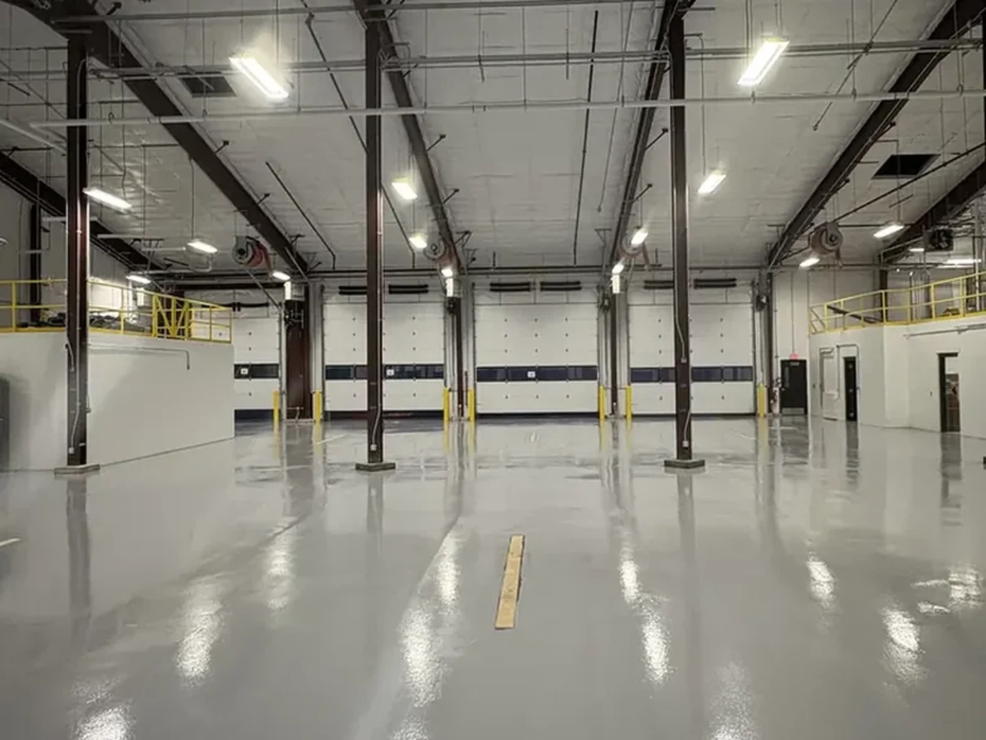 Solid color epoxy floor across a commercial vehicle bay with dock doors